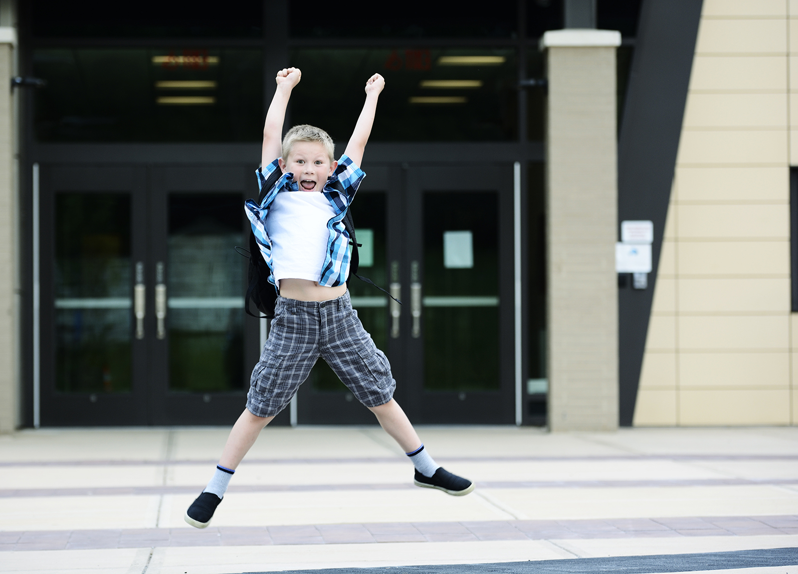 Happy boy jumping in the front of the school.