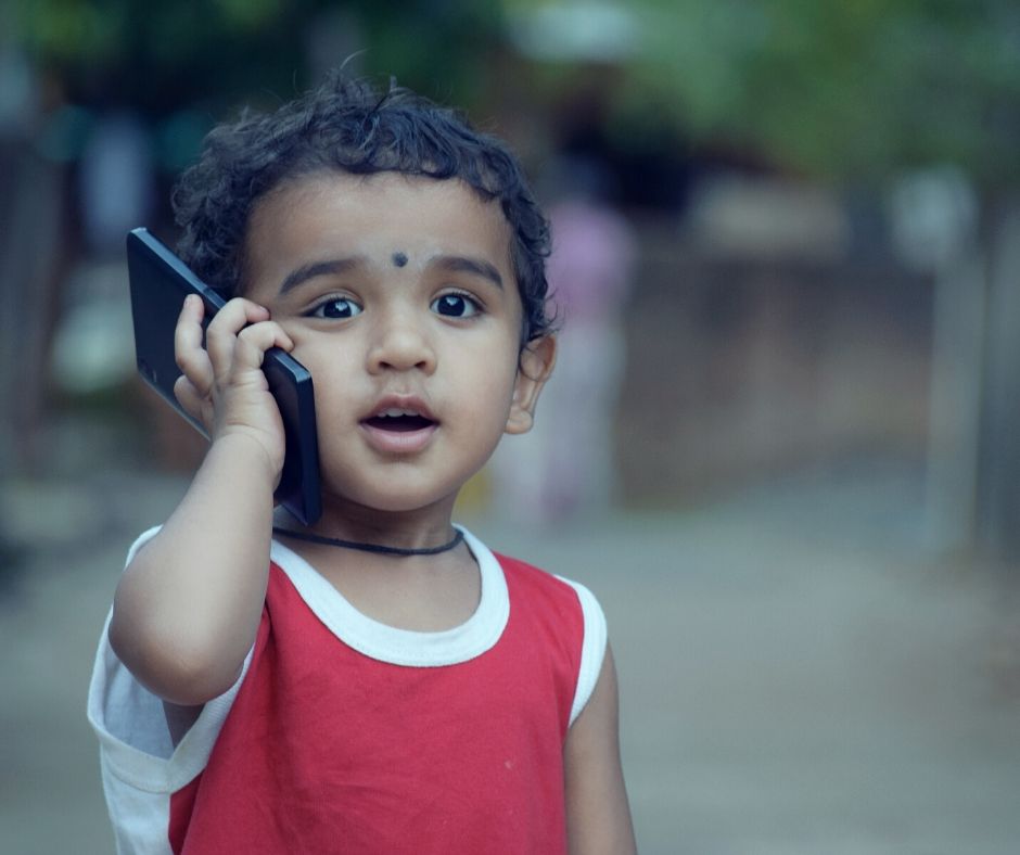 a toddler using a cellphone and smiling
