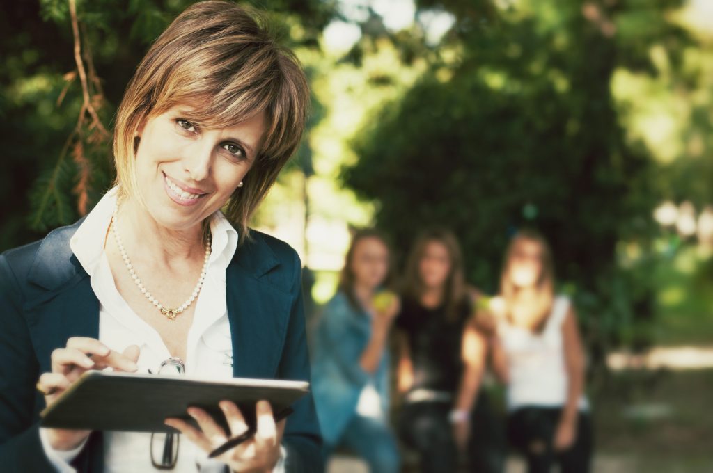 Teacher-Using-a-Tablet-students-in-the-background